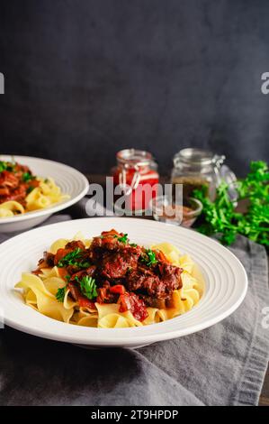 Goulash tedesco servito su tagliatelle di uova in una ciotola poco profonda: Pezzi di manzo bolliti conditi con marjoram, semi di carvi e paprika Foto Stock