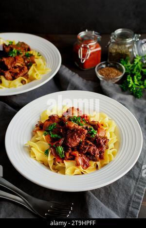 Goulash tedesco servito su tagliatelle di uova in bocce poco profonde: Pezzi di manzo bolliti conditi con marjoram, semi di carvi e paprika Foto Stock