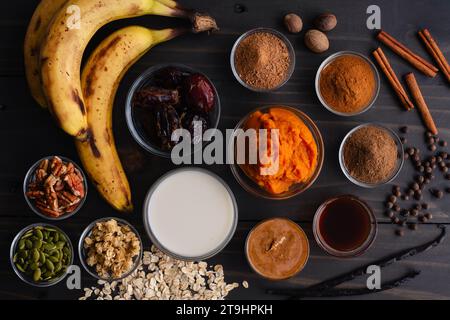 Ciotola per frullato di zucca ingredienti su un tavolo di legno: Purea di zucca, datteri, burro di mandorle e altri ingredienti per una colazione vegana con frullato Foto Stock