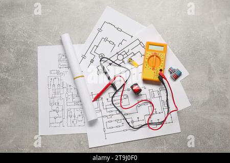 Schemi elettrici, multimetro digitale e connettori su tavola grigia, posizionamento piatto Foto Stock