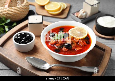 Zuppa di solyanka di carne con salsicce, olive e verdure in ciotola servita su tavola grigia Foto Stock