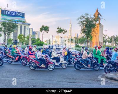 Vietnam, traffico motociclistico ho chi Minh nell'ora di punta. Statua di Tran Hung Dao, eroe militare del XIII secolo sullo sfondo. Foto Stock