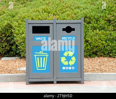 bidoni della spazzatura in un parco con cespugli sullo sfondo. Discarica e riciclaggio. Foto Stock