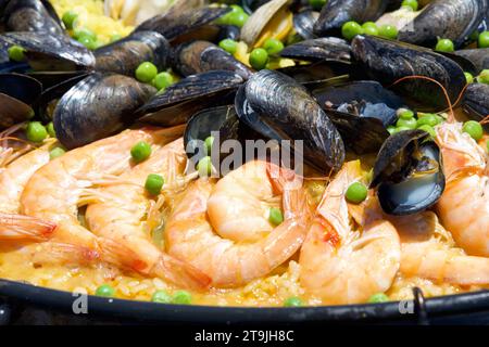 Primo piano su vongole, muscoli, riso di gamberi e piselli cucinati in un gigantesco wok all'aperto. Paella tradizionale Foto Stock