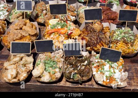 Chiudere i contenitori di fast food su un tavolo marrone con etichette vuote. Feci fritte, cavolfiore, grigliate e con formaggio blu Foto Stock