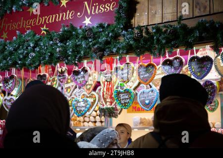 Outlet di vendita ambulante che vende torta al cioccolato a forma di cuore e visitatori affollati al mercatino di Natale (Wiener Christkindlmarkt) di sera in inverno Foto Stock