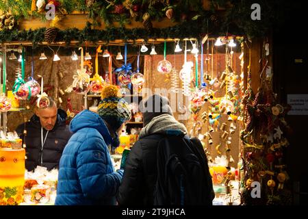 Venditori ambulanti che vendono decorazioni natalizie e visitatori affollati al mercatino di Natale (Wiener Christkindlmarkt) di sera d'inverno, Vienna Foto Stock