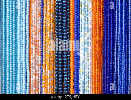 primo piano su corde di perline in blu, arance e viola. Decorazioni per capelli popolari in alcune culture. Foto Stock