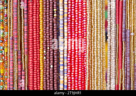 primo piano su corde di perline in rosso, giallo, rosa. Decorazioni per capelli popolari in alcune culture. Foto Stock