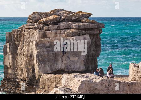 A Man Climbing Pulpit Rock, Portland Bill, Isle of Portland, Dorset, Regno Unito Foto Stock