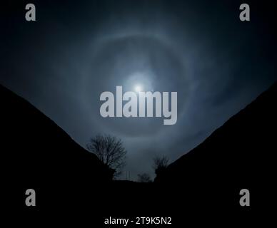 Un alone solare si forma intorno alla luna piena in una fredda notte di novembre, Worcestershire, Inghilterra. Il pianeta Giove può essere visto a destra della luna. Foto Stock