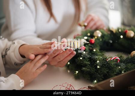 Selezione intermedia di creazione della corona di Natale. Mamma e figlia si preparano per le vacanze invernali Foto Stock