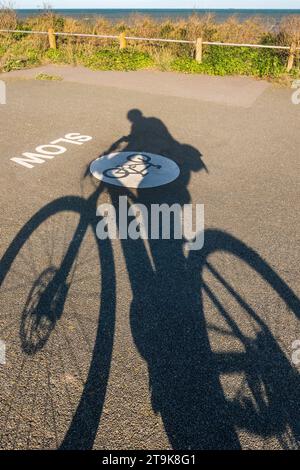 Ombra di un ciclista su una pista ciclabile costiera a Margate Kent, Regno Unito Foto Stock