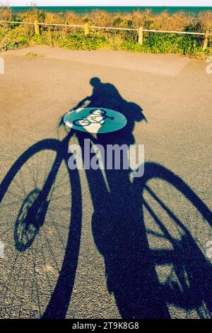 Ombra di un ciclista su una pista ciclabile costiera a Margate Kent, Regno Unito Foto Stock