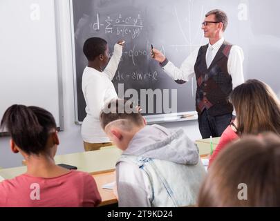 Uno studente africano risponde alla lavagna in una lezione di matematica Foto Stock