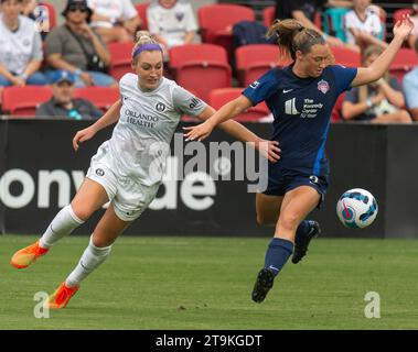 Due calciatrici che corrono e calciano una palla su un campo in erba in una partita attiva Foto Stock