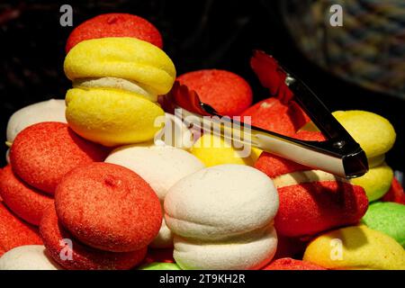 Un primo piano di macaron colorati con un paio di pinze sulla parte superiore. Foto Stock