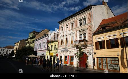 La gente cammina lungo gli edifici storici lungo via Nicolae Bălcescu a Sibiu, Romania, 1 agosto 2023. Foto di Tim Chong Foto Stock