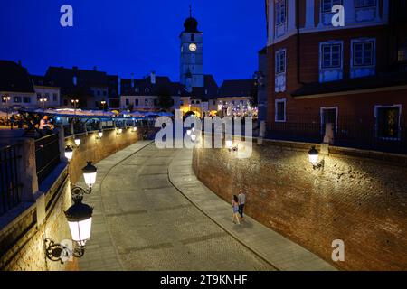 Un paio di passeggiate lungo Ocnei Street verso Council Tower a Sibiu, Romania, 1 agosto 2023. Nel mezzo è raffigurata la foto di Tim Chong Foto Stock