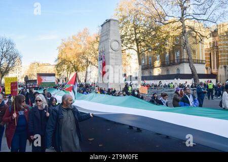 Londra, Regno Unito. 25 novembre 2023. I manifestanti hanno una gigantesca bandiera palestinese accanto al monumento Cenotafio durante la manifestazione a Whitehall. Migliaia di persone hanno marciato nuovamente nel centro di Londra in solidarietà con la Palestina chiedendo un cessate il fuoco mentre la guerra Israele-Hamas continua. Credito: SOPA Images Limited/Alamy Live News Foto Stock