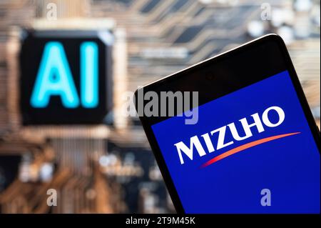 In questa foto, il logo della multinazionale giapponese di servizi bancari e finanziari Mizuho Bank è visualizzato su uno smartphone con un chip e un simbolo di intelligenza artificiale (ai) sullo sfondo. Foto Stock