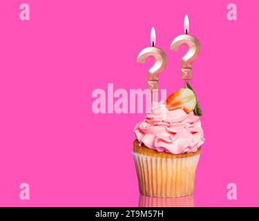 Torta di compleanno con punto interrogativo a due candele - su sfondo rosa caldo. Foto Stock