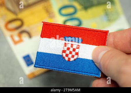 Simbolo dell'euro della Croazia, stemma della Croazia tenuto in mano sullo sfondo delle banconote da 50 e 100 euro, ingresso della Croazia nell'area dell'euro, Unione europea" Foto Stock