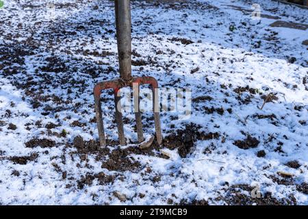 Primo piano di una forca di scavo da giardino bloccata in un terreno ghiacciato. Foto Stock