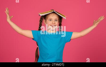 Deliziata preadolescente con trecce che bilanciano il notebook aperto sulla testa Foto Stock