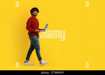 Un indù positivo che usa il notebook e cammina verso lo spazio di copia Foto Stock