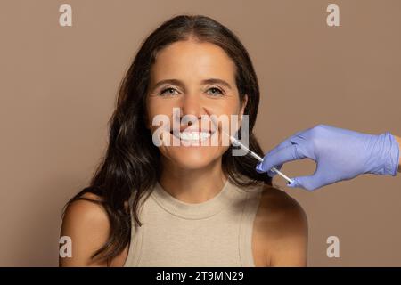 Allegra signora caucasica anziana, godere di cure di bellezza professionali, estetista fa iniezione Foto Stock