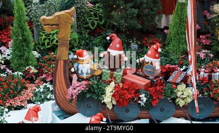 Babbo Natale e gnomi in barca, circondati da alberi in un ambiente vivace Foto Stock