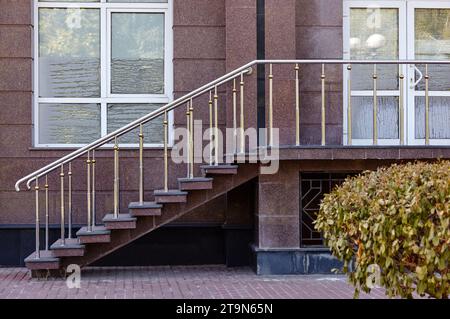 Soglia con gradini con recinzione in ferro di ramoscelli. Parete in marmo con finestre e ingresso all'ufficio Foto Stock