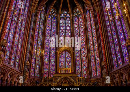 Sfumature radiose ballano nella luce sacra di Sainte Chapelle, rivelando la bellezza senza tempo della vetrata artistica che si trova nel cuore di Parigi, in Francia. Foto Stock