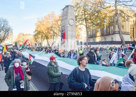 Londra, Regno Unito. 25 novembre 2023. I manifestanti passano davanti al cenotafio a Whitehall con una gigantesca bandiera palestinese. Migliaia di persone hanno marciato di nuovo nel centro di Londra in solidarietà con la Palestina mentre la guerra Israele-Hamas continua. Credito: Vuk Valcic/Alamy Live News Foto Stock