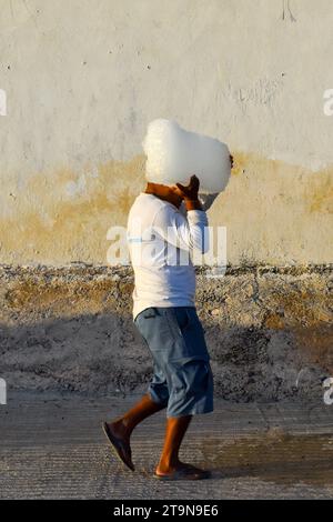 Pescatore che porta blocchi di ghiaccio nel villaggio di pescatori di El Cuyo, Yucatan, messico Foto Stock