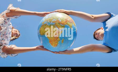 Una ragazza e un ragazzo girano un globo del mondo. Il concetto di pace e creazione. Foto Stock