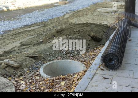 Costruzione di lavori in terra per la raccolta delle acque reflue che frantumano strade asfaltate Foto Stock