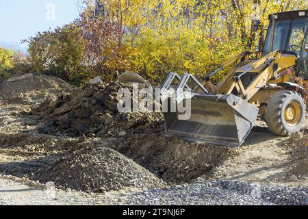 Durante la ricostruzione dell'autostrada, un escavatore livella il terreno per la costruzione di strade Foto Stock