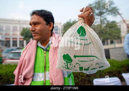 Nuova Delhi, India. 26 novembre 2023. Un lavoratore della NDMC distribuisce pacchetti di fertilizzanti compost gratuiti realizzati con rifiuti presso la discarica di Delhi durante la giornata di Raahgiri a Connaught Place, nuova Delhi. Il Raahgiri Day è organizzato dalla polizia stradale di Delhi e dalla New Delhi Municipal Corporation (NDMC). Si tratta della prima iniziativa sostenuta dei cittadini senza auto in India che promuove la sicurezza di pedoni e ciclisti, una vita sana e collega le comunità recuperando le strade cittadine e gli spazi pubblici, con l'obiettivo finale di recuperare vite urbane. Credito: SOPA Images Limited/Alamy Live News Foto Stock