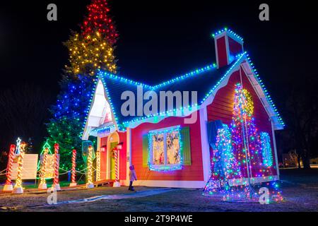 Decorazioni natalizie, gente della scena natalizia, bambino fuori casa di Babbo Natale, giorno di Natale, albero di Natale all'aperto con luci di Natale Foto Stock