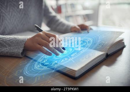 Donna che legge un libro di astrologia. Proiezione della ruota astrologica, scegliere un segno zodiacale. Concetto esoterico astrologico. Foto Stock