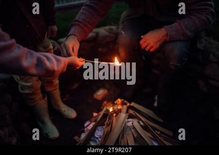 La famiglia trascorre la serata all'aperto, accendendo il fuoco in una fossa. Prents e i bambini trascorrono del tempo in famiglia di qualità. Foto Stock