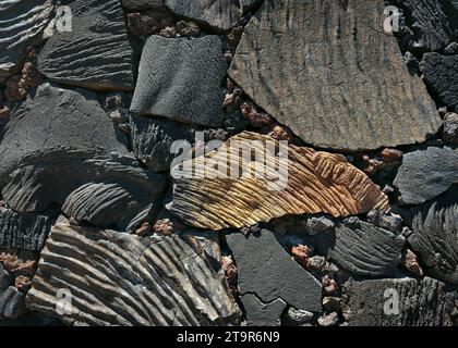Parete in pietra di roccia vulcanica in diverse dimensioni, forme e sfumature di colore. Muratura vintage realizzata in pile di pietre naturali. Foto Stock