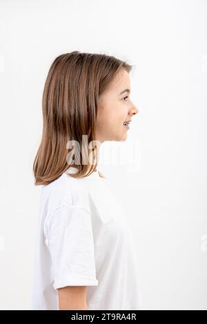 Bruna ragazza sorridente con l'apparecchio sui denti su uno sfondo bianco isolato. Foto Stock