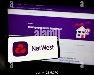 Persona che possiede uno smartphone con il logo della società finanziaria National Westminster Bank (NatWest) davanti al sito Web. Concentrarsi sul display del telefono. Foto Stock