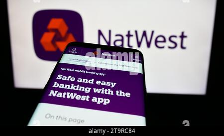 Telefono cellulare con sito Web della società finanziaria National Westminster Bank (NatWest) davanti al logo aziendale. Mettere a fuoco in alto a sinistra sul display del telefono. Foto Stock