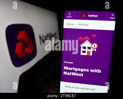 Persona che possiede uno smartphone con pagina Web della società finanziaria National Westminster Bank (NatWest) con logo. Concentrarsi sul centro del display del telefono. Foto Stock