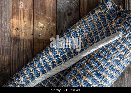 Tappeto in denim geometrico intrecciato a mano su pavimento in legno. Foto Stock