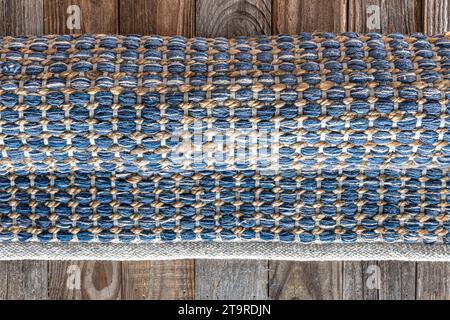 Tappeto in denim geometrico intrecciato a mano su pavimento in legno. Foto Stock